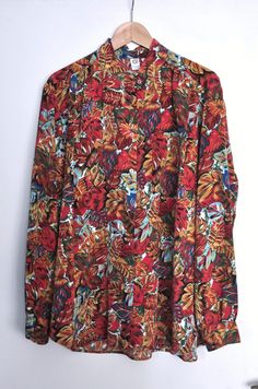 Vintage print polyester blouse, from the 1990s Womens hipster blouse, featuring a vivid print of various leaves in red, ochre yellow, blue and green! Blouse has an oversized free falling shape and a high neck collar. Size - 48 EU, which is 18 EU or XL / XXL Approximate. Measurements: Shoulder to Shoulder (from seam to seam) - 18.5 inches / 47 cm Sleeve length - 24 inches / 61 cm Armpit to armpit - 26 inches / 66 cm Length of the back ( without collar) - 29.1 inches / 74 cm Condition - Excellent Retro Tops With Vibrant Print For Fall, Retro Vibrant Print Tops For Fall, Red Tops With Vibrant Print For Fall, Vibrant Print Long Sleeve Shirt For Fall, Long Sleeve Shirt With Tropical Print For Spring, Long Sleeve Shirt With Vibrant Print For Fall, Multicolor Floral Print Tops For Fall, Retro Floral Print Blouse For Fall, Red Top With Vintage Print For Spring