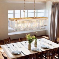 a dining room table with plates and silverware on it in front of a window