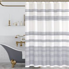 a bath tub sitting next to a shower curtain in a white and blue bathroom with gold fixtures