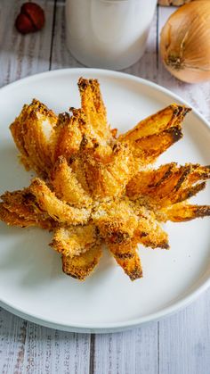 some fried food on a white plate next to a glass of milk and garlic flakes