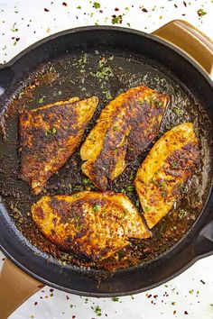 three pieces of chicken cooking in a skillet