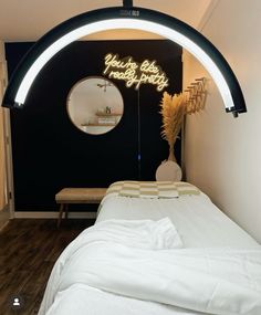 a white bed sitting under a neon sign