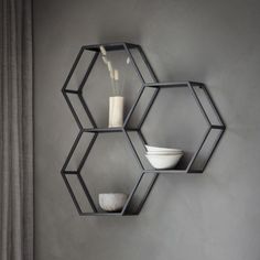 hexagonal shelves with bowls and vases on them against a gray wall in a living room