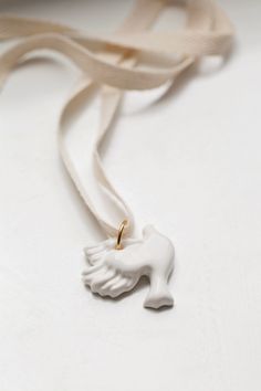 White Dove Porcelain Handmade Pendant is a symbol of peace and love, and is handcrafted by skilled artisans of Yaglyna.

Made with high-quality long-lasting porcelain material.
Width - 4.2 cm / 1.5", Length - 4 cm /1.6"
Necklace – 2 cotton ribbons (black and beige), length - 1 meter / 40"

2 varialtions of Metal of the ring
1) gold tone costume jewelry metal
2) silver tone costume jewelry metal

Each pendant is carefully wrapped in a natural branded sack.
♥ All Ceramic Jewellery is shipped in a beautiful gift box White Ceramic Jewelry Gift, White Ceramic Jewelry As A Gift, White Ceramic Jewelry For Gifts, Dove Pendant, Porcelain Handmade, Ceramic Jewellery, Symbol Of Peace, White Dove, Personalized Stamps