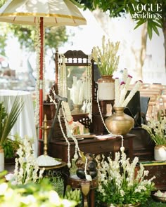 there are many vases and flowers on display in this garden setting with an umbrella over them