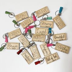 a bunch of wooden keychains that have some words on them with tassels