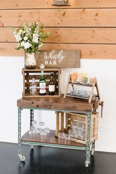 a bar cart with wine glasses on it and a sign that says whiskey bar next to it