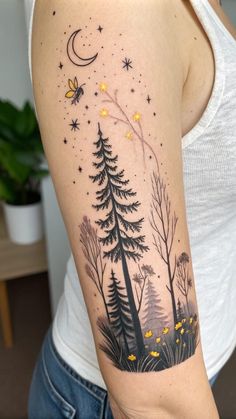 a woman's arm with a forest scene and stars in the sky on it