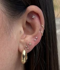 a woman wearing gold ear piercings with stars and moon designs on her left ear