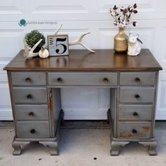 an old desk has been painted silver with gold and white flowers on the top, along with antlers