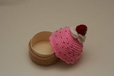 a pink knitted hat sitting on top of a wooden box next to an empty container