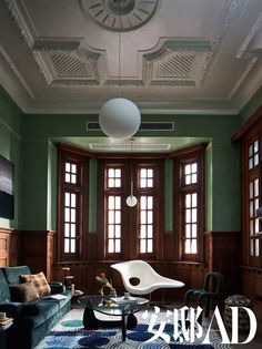 a living room with green walls and wooden trimmings on the ceiling, along with an area rug