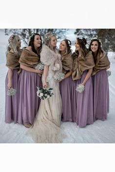 a group of women standing next to each other in the snow wearing dresses and fur stoles