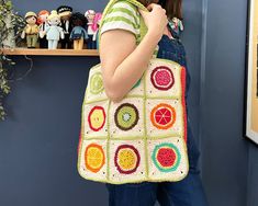 a woman carrying a crocheted granny bag in front of a shelf full of toys