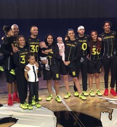 a group of people standing on top of a basketball court with their arms around each other