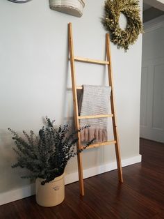 a ladder leaning against the wall next to a potted plant with a wreath on it