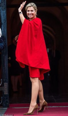 a woman in a red dress waves to the crowd