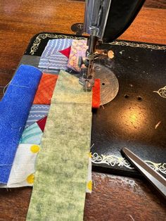 a close up of a sewing machine on a table with fabric and scissors next to it