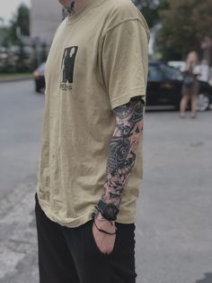 a man with tattoos on his arm standing in the street