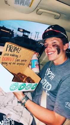 a man sitting in the back seat of a car holding a box of donuts