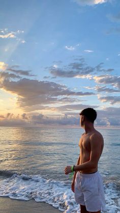 a man standing on top of a beach next to the ocean