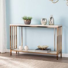 a console table with two vases and a book on it in front of a blue wall