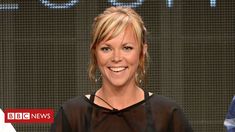 a woman is smiling while standing in front of a screen with the bbc news logo behind her