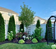 a garden with trees, bushes and flowers in it