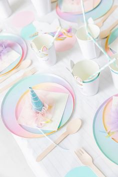 the table is set with pastel plates and unicorn napkins