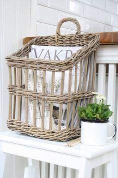 a wicker basket sitting on top of a white table next to a potted plant