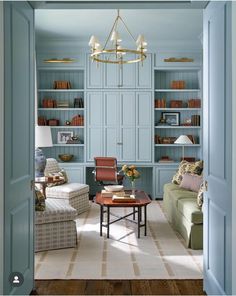 a living room filled with furniture and bookshelves next to a doorway that leads to a sitting area