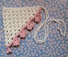 a crocheted triangle with pink and white flowers on a blue floraled background