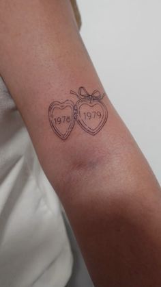 a woman's arm with two heart shaped tattoos on the left side of her arm