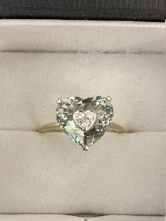 "This stunning ring is made from 14-karat two tone gold and set with beautiful heart shape of mint-green amethyst that set with three small sparkling diamonds at the center of the amethyst - which is said to have a calming effect on the soul and spirit. We believe this would be a thoughtful gift to give or treat to yourself. Material: 14k two tone gold Stone/Pendant: Green amethyst measures approximate 12.5 x 12.0 mm Diamonds: Approximate weigh 0.10-carats total Ring size: 9 US Weight: 3.3 grams Green Heart Cut Diamond Ring For Anniversary, Anniversary Green Amethyst Ring In Yellow Gold, Yellow Gold Green Amethyst Ring For Anniversary, Green Heart Cut Diamond Ring, Heart Cut Amethyst Ring With Accent Stones For Anniversary, Green Amethyst Ring With Center Stone For Anniversary, Anniversary Green Amethyst Ring In Fine Jewelry Style, Fine Jewelry Green Amethyst Ring For Anniversary, Soul And Spirit