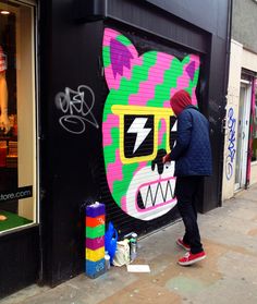 a man is painting a mural on the side of a building in front of a store