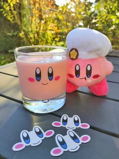 a pink drink sitting on top of a wooden table next to a stuffed animal toy