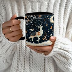 a woman is holding a coffee mug with a deer on it and stars in the sky