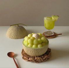 there is a bowl full of fruit on the table next to a glass and spoon