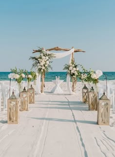 an outdoor wedding setup on the beach with white flowers and greenery in vases