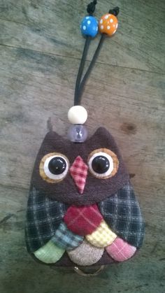 an owl keychain hanging on a wooden surface with two balls attached to it