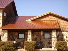 the front of a building with stone and metal roofing