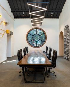 an empty conference room with a large round window in the center and black leather chairs around it