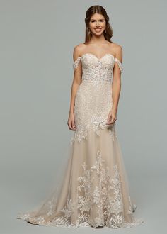 a woman in an off the shoulder wedding dress with sheer lace and appliques