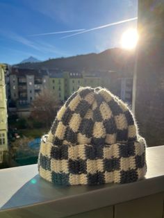 a knitted hat sitting on top of a window sill next to a building