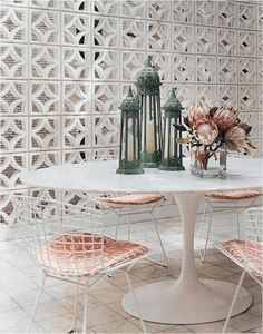 a white table with four chairs in front of it and some flowers on the table