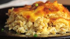 a black plate topped with rice and meat covered in cheese on top of green onions