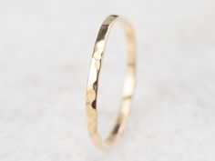 a close up view of a gold wedding ring on a white surface with no background