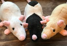 three stuffed animals laying next to each other on a brown blanket with white and black ones