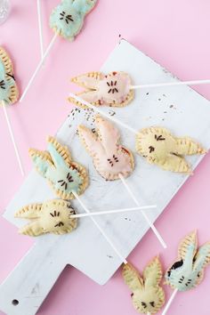 small pastries are sitting on toothpicks on a pink surface