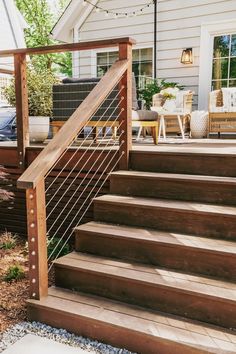 a set of wooden steps leading up to a patio with string lights on the side